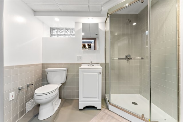 full bathroom with toilet, a wainscoted wall, a sink, tile walls, and a stall shower