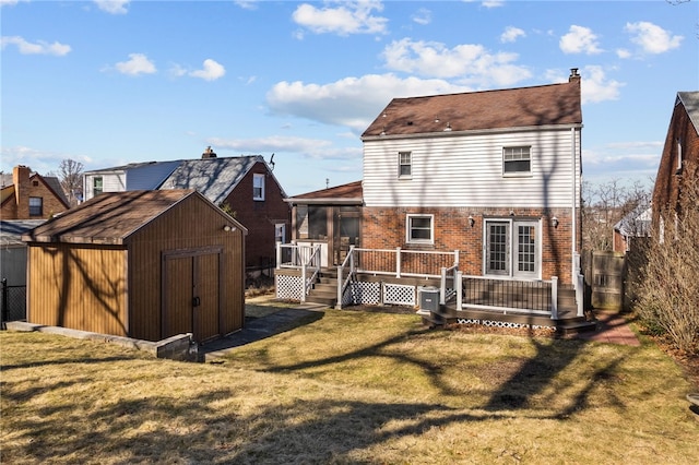 rear view of house featuring brick siding, a yard, a deck, a shed, and an outdoor structure