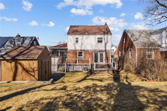 back of house featuring a lawn, a storage unit, a wooden deck, an outdoor structure, and brick siding