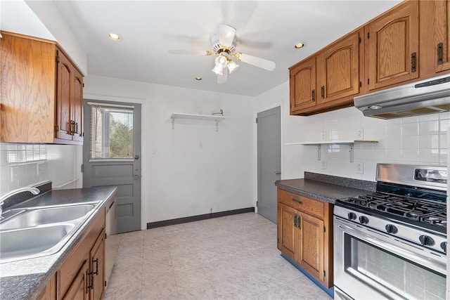 kitchen with appliances with stainless steel finishes, brown cabinets, a sink, and under cabinet range hood