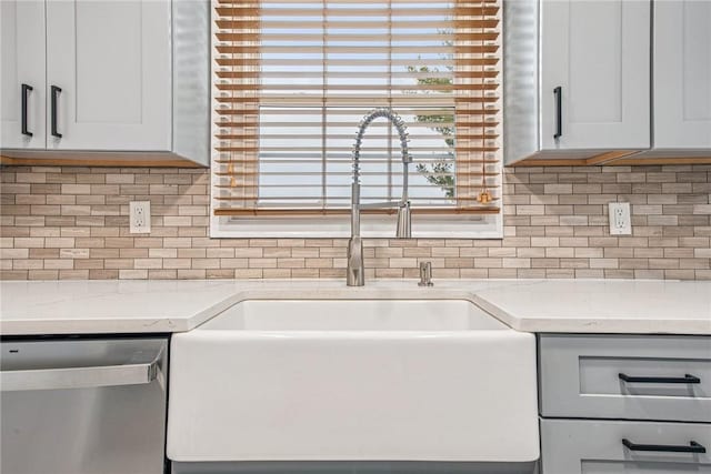 kitchen featuring tasteful backsplash, a sink, light stone counters, and stainless steel dishwasher