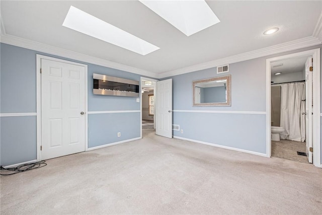 unfurnished bedroom featuring a skylight, carpet flooring, visible vents, baseboards, and crown molding