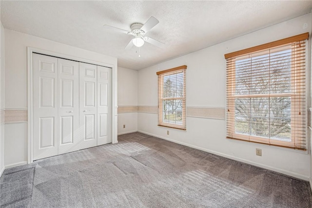 unfurnished bedroom with baseboards, a ceiling fan, a textured ceiling, carpet floors, and a closet