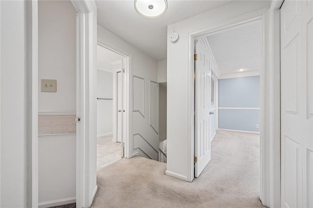 corridor featuring carpet floors, ornamental molding, and baseboards