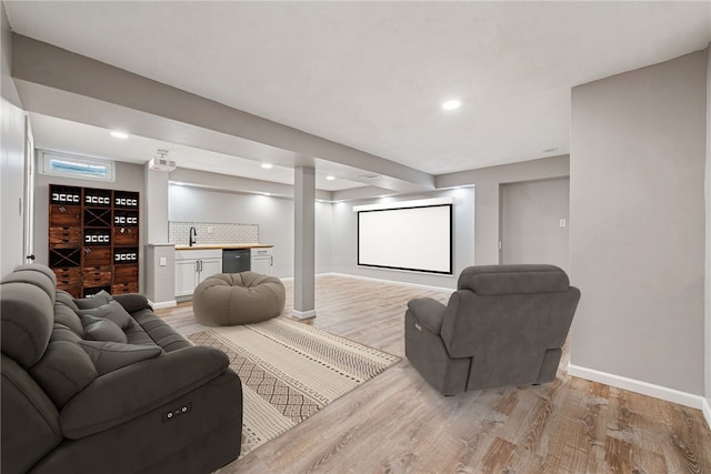 living area featuring recessed lighting, baseboards, light wood-style floors, bar, and ornate columns