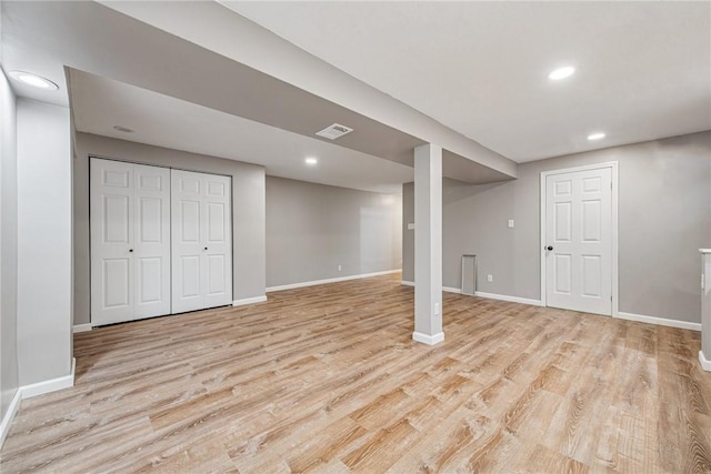 finished below grade area featuring light wood-style flooring, visible vents, and baseboards