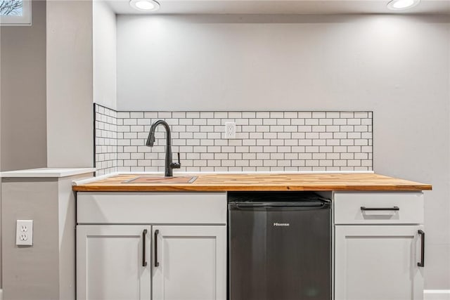 kitchen with butcher block counters, white cabinetry, tasteful backsplash, and a sink