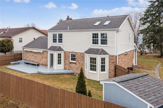 back of house featuring a shingled roof, a fenced backyard, a deck, a yard, and brick siding