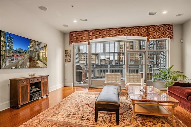 living room featuring recessed lighting, wood finished floors, visible vents, and baseboards