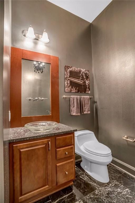 half bath featuring marble finish floor, vanity, and toilet