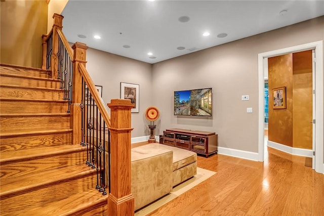 staircase with baseboards, wood finished floors, and recessed lighting