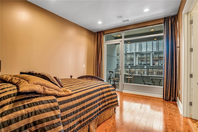 bedroom featuring access to exterior, hardwood / wood-style floors, and recessed lighting