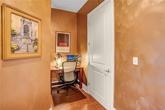 office area featuring built in desk, baseboards, and wood finished floors