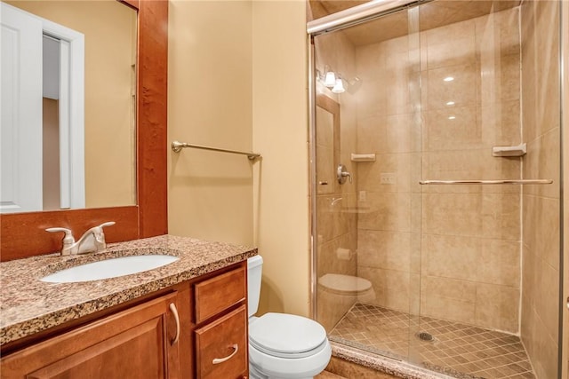 bathroom featuring toilet, a shower stall, and vanity