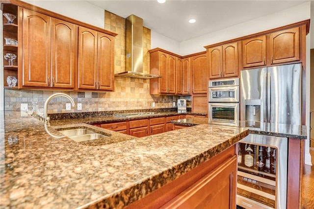 kitchen with wine cooler, stainless steel appliances, decorative backsplash, a sink, and wall chimney range hood