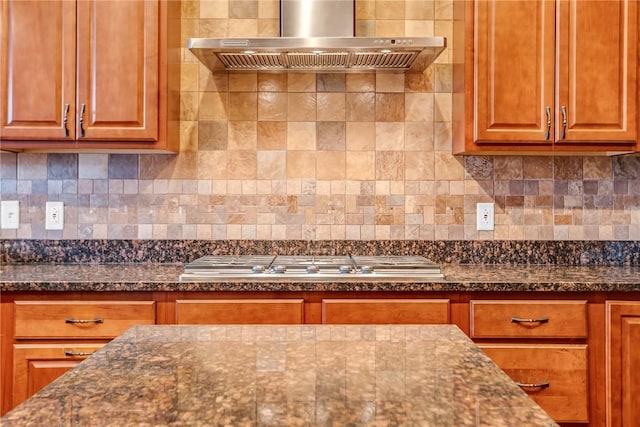 kitchen featuring dark stone countertops, stainless steel gas stovetop, decorative backsplash, and exhaust hood