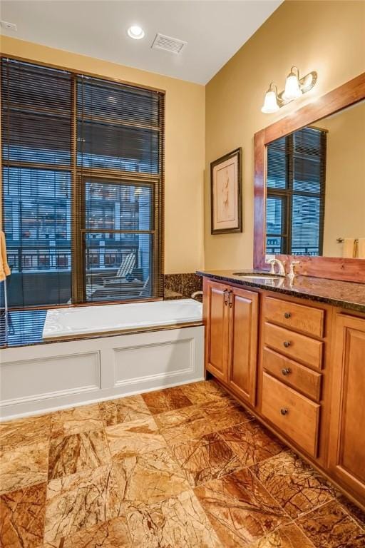 full bath with a garden tub, a sink, visible vents, and double vanity