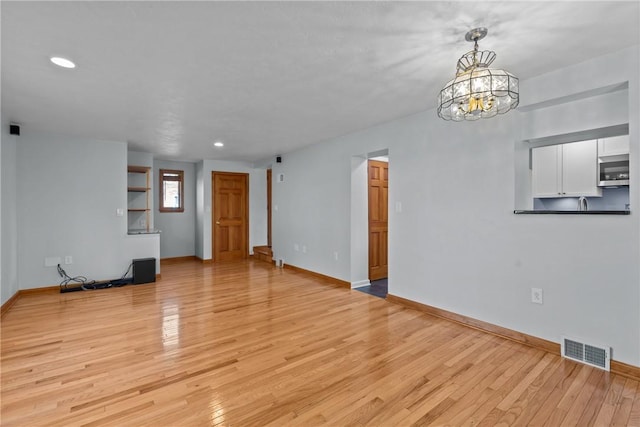 unfurnished living room featuring light wood finished floors, baseboards, and visible vents