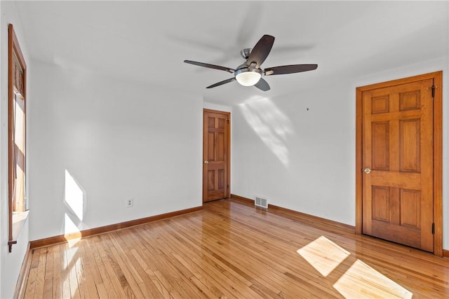 unfurnished room featuring light wood-style floors, visible vents, baseboards, and a ceiling fan