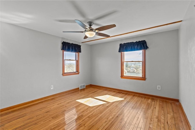 unfurnished room featuring ceiling fan, light wood finished floors, visible vents, and baseboards