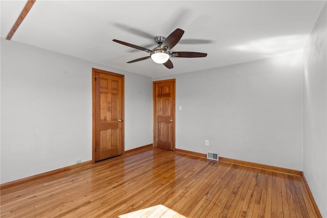 empty room with ceiling fan, light wood-style flooring, visible vents, and baseboards