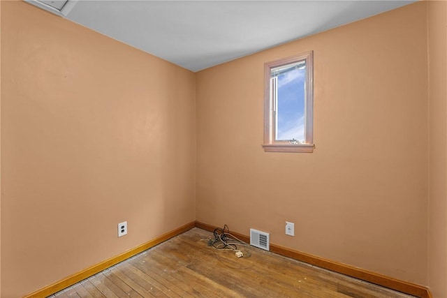 spare room featuring light wood-style floors, visible vents, and baseboards