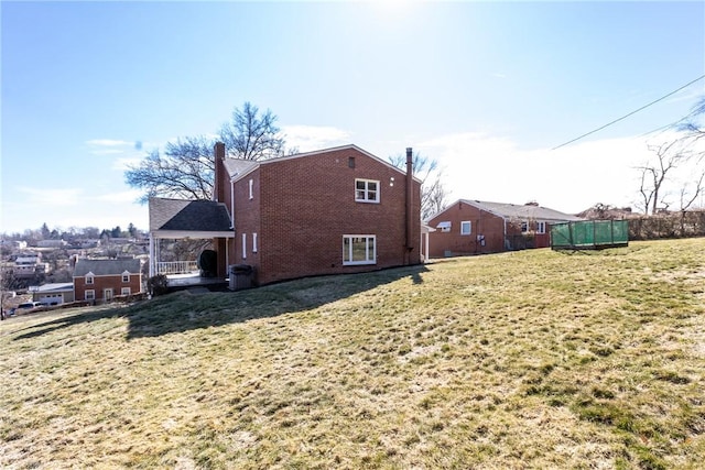 view of side of property featuring brick siding, a lawn, and central air condition unit