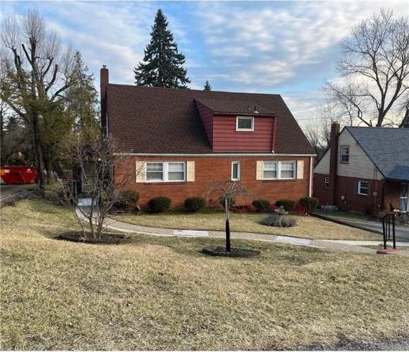 view of front of property featuring brick siding, a chimney, and a front lawn