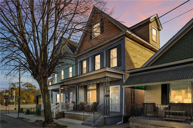 victorian-style house with a porch and brick siding