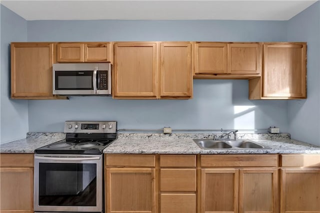 kitchen with light brown cabinets, appliances with stainless steel finishes, a sink, and light stone countertops