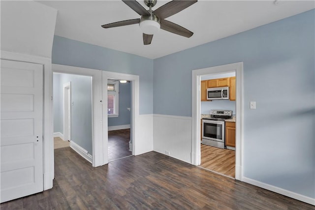 spare room featuring a wainscoted wall, wood finished floors, and a ceiling fan