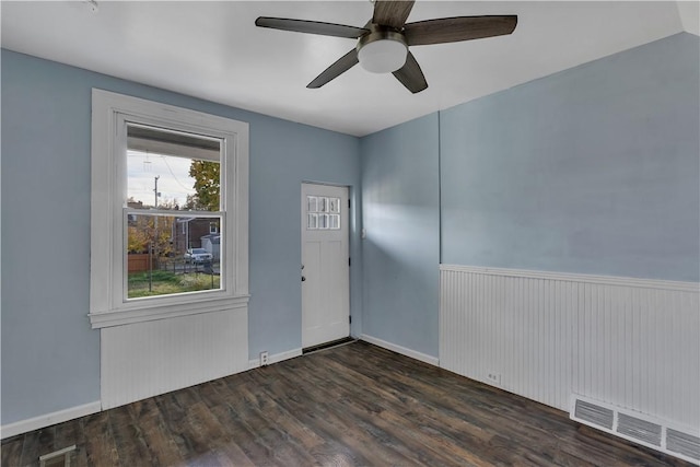 interior space featuring a ceiling fan, dark wood-style flooring, visible vents, and wainscoting