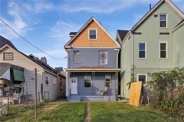 rear view of house featuring a porch, fence, and a lawn