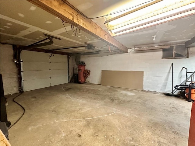 garage with concrete block wall, gas water heater, and a garage door opener