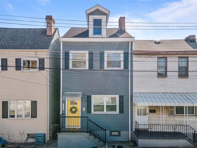 townhome / multi-family property with roof with shingles and a chimney