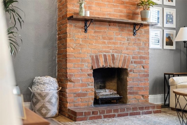 interior details with a brick fireplace, a textured wall, and baseboards