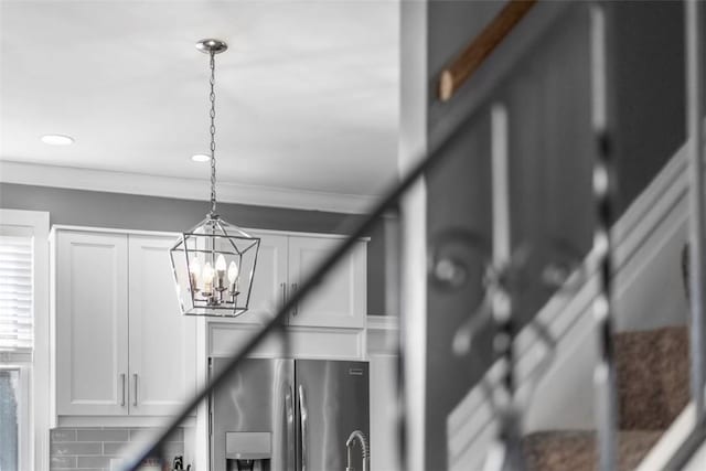 room details with decorative light fixtures, stainless steel refrigerator with ice dispenser, recessed lighting, ornamental molding, and white cabinetry