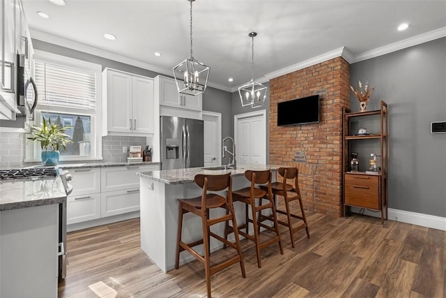 kitchen featuring white cabinets, stainless steel fridge with ice dispenser, light stone counters, light wood-type flooring, and a sink