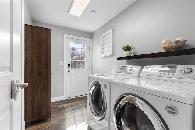 washroom featuring laundry area, washing machine and clothes dryer, dark wood finished floors, and baseboards