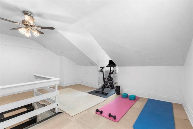 exercise room featuring a ceiling fan, vaulted ceiling, and baseboards