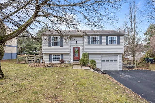 raised ranch with a garage, aphalt driveway, a front yard, and fence