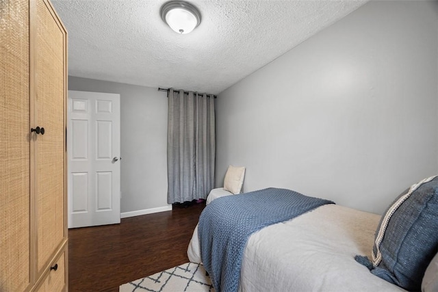 bedroom featuring a textured ceiling, wood finished floors, and baseboards