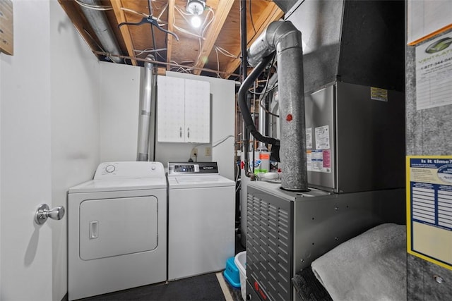 clothes washing area with independent washer and dryer, cabinet space, and heating unit