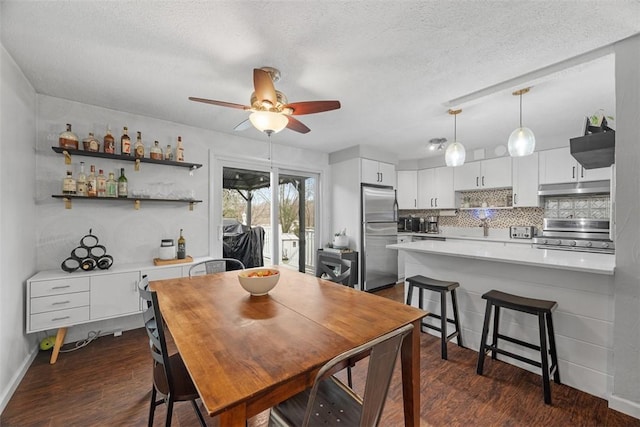 dining room with a ceiling fan, dark wood-style flooring, a textured ceiling, and baseboards