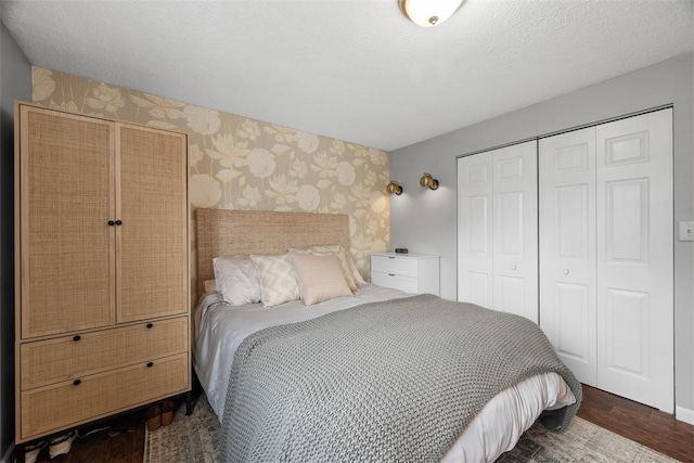 bedroom featuring wallpapered walls, a textured ceiling, dark wood-style flooring, and a closet