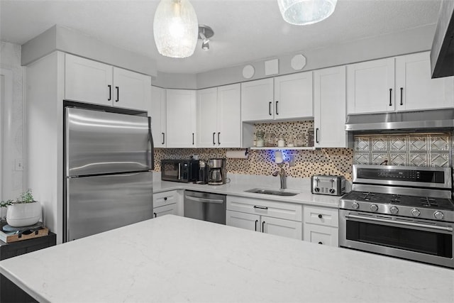 kitchen featuring stainless steel appliances, tasteful backsplash, white cabinets, a sink, and under cabinet range hood