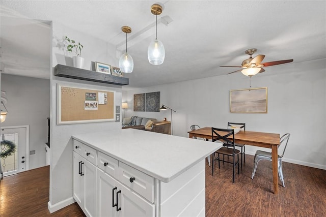 kitchen featuring dark wood-style floors, light countertops, white cabinetry, a peninsula, and baseboards