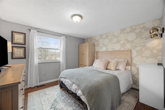 bedroom with wallpapered walls, baseboards, visible vents, dark wood-style flooring, and a textured ceiling