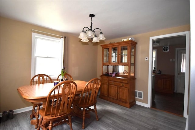 dining space with an inviting chandelier, visible vents, baseboards, and wood finished floors