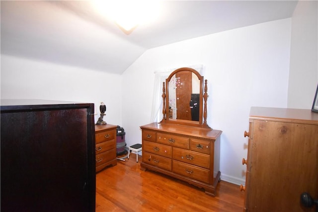 bedroom with vaulted ceiling and light wood-style floors